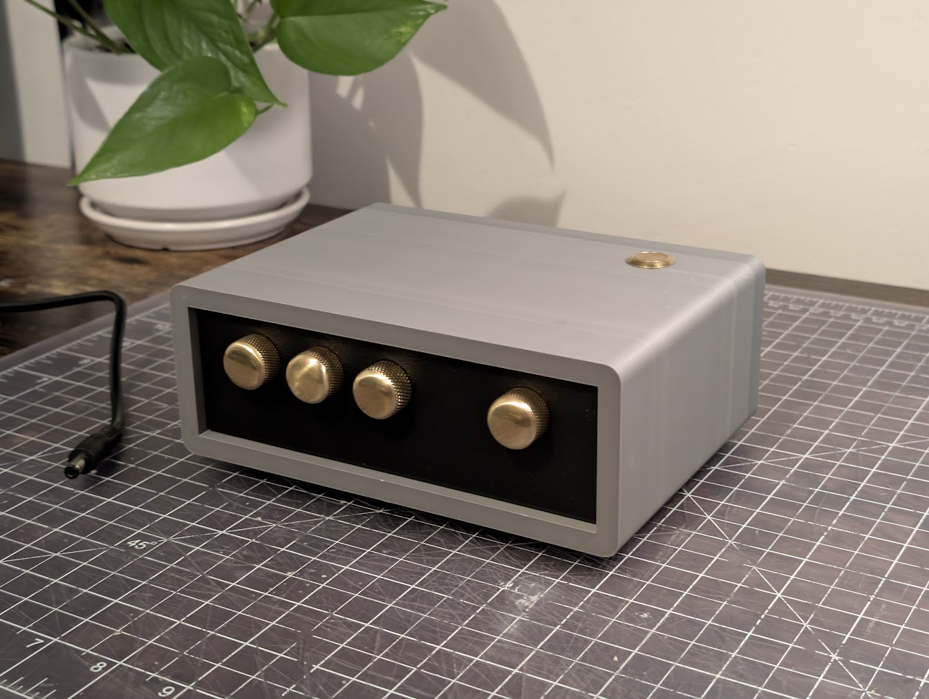 Sleep Machine prototype on a workbench, with a light enclosure, black front panel, four brass knobs, and a brass top button