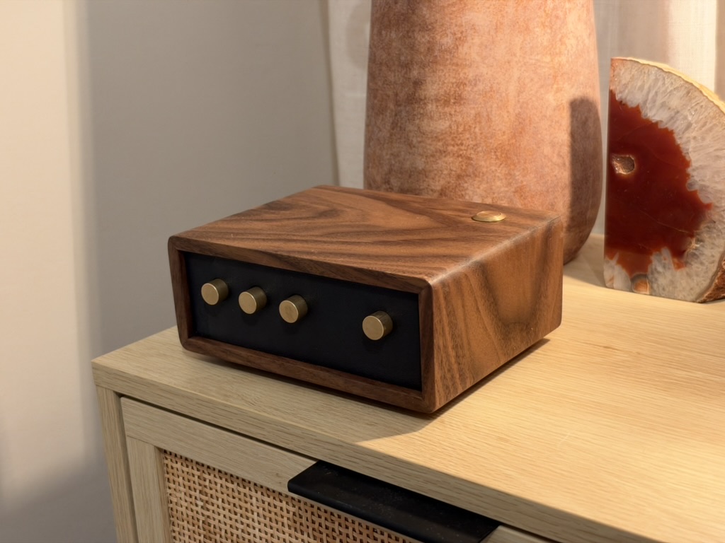 Sleep Machine walnut enclosure prototype with a black front panel, four brass knobs, and a brass top button
